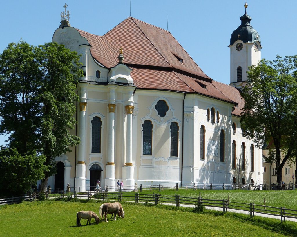 Wieskirche Außenaufnahme im Sonnenlicht mit 2 Pferden auf der Wiese